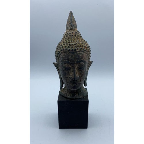 247 - A small metal Buddhist head on wooden stand