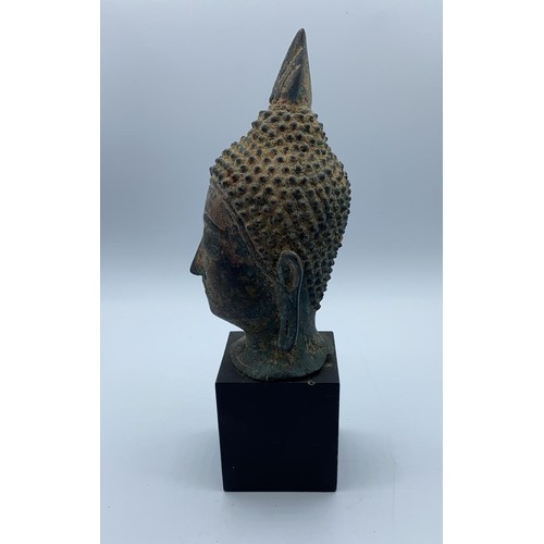 247 - A small metal Buddhist head on wooden stand