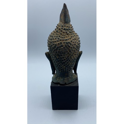 247 - A small metal Buddhist head on wooden stand