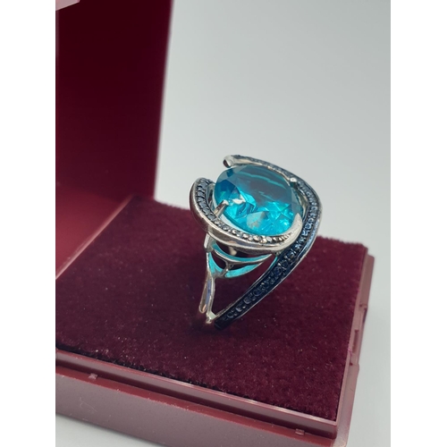 283 - Silver ring having a large turquoise stone with a sweeping marquisette setting and surround. Clear 9... 