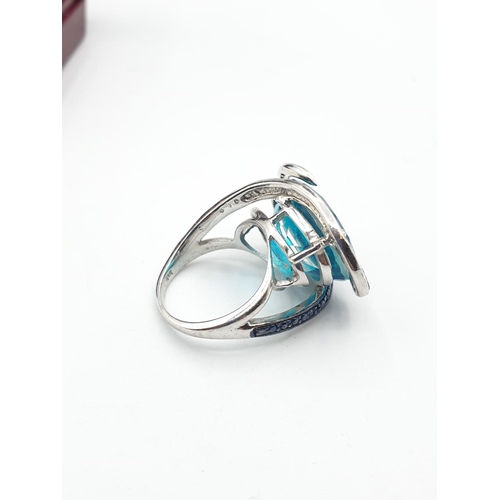 283 - Silver ring having a large turquoise stone with a sweeping marquisette setting and surround. Clear 9... 