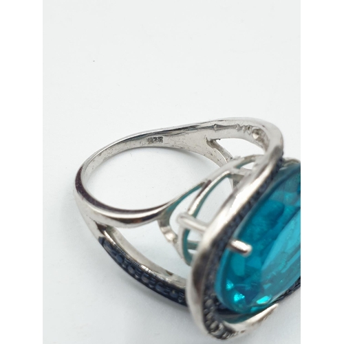 283 - Silver ring having a large turquoise stone with a sweeping marquisette setting and surround. Clear 9... 