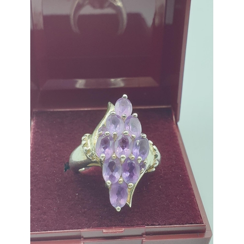 292 - Stone set silver ring, with a boat shape setting. Having 9 oval amethysts and silver beading to side... 