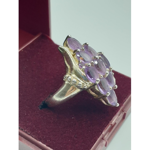 292 - Stone set silver ring, with a boat shape setting. Having 9 oval amethysts and silver beading to side... 