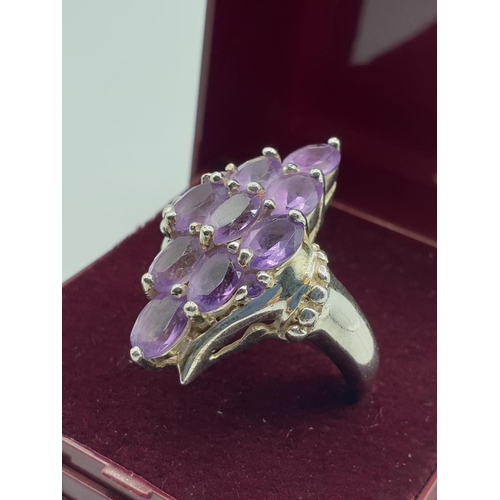 292 - Stone set silver ring, with a boat shape setting. Having 9 oval amethysts and silver beading to side... 