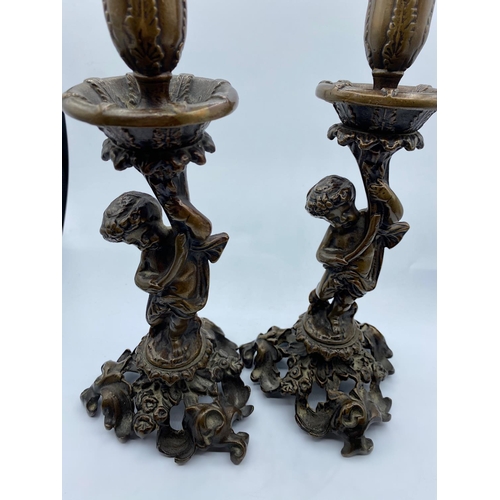 95 - A Pair of Antique Bronze Candlesticks with Cherubs, weight 2.9kg and 26cm tall (2)