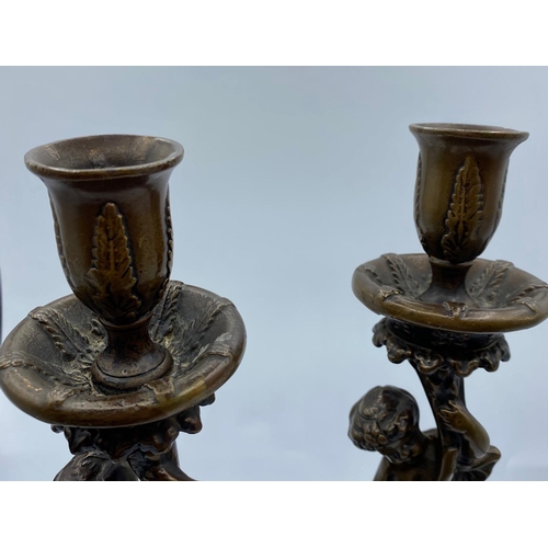 95 - A Pair of Antique Bronze Candlesticks with Cherubs, weight 2.9kg and 26cm tall (2)