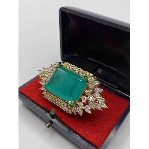 22 - A dress ring with simulated emerald (25x18mm) and sapphires marked 18KGL, designed and signed by 