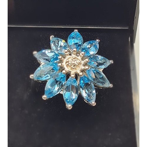 329 - Stone Set Silver Ring in the form of a large flower. Having a 10 turquoise coloured stone surrounded... 