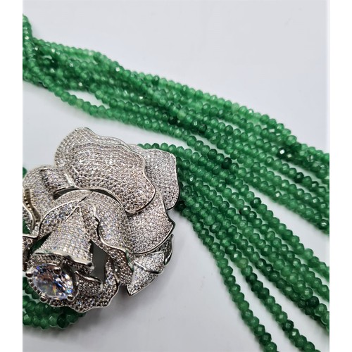 54 - An impressive six row faceted emerald necklace with a white metal and cubic zirconia ornamental rose... 