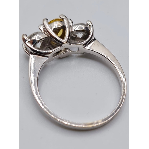 176 - 18ct white gold three stone ring. Having a yellow topaz oval centre stone flanked  by two large clea... 