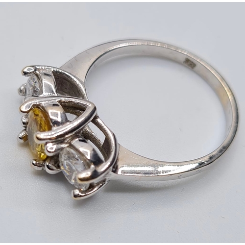 176 - 18ct white gold three stone ring. Having a yellow topaz oval centre stone flanked  by two large clea... 