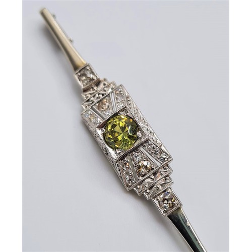 19 - An antique art deco platinum bar brooch with diamonds and central peridot 4.8  grams and length 55cm... 