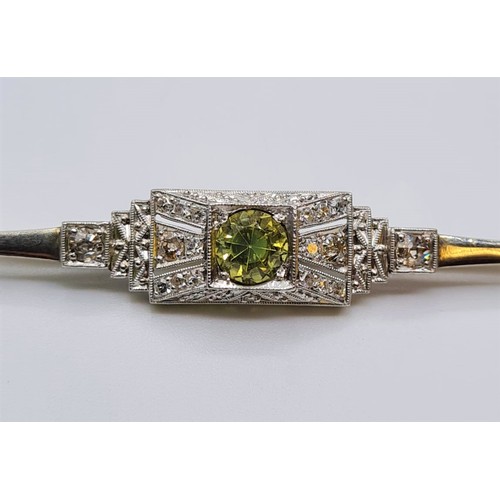 19 - An antique art deco platinum bar brooch with diamonds and central peridot 4.8  grams and length 55cm... 