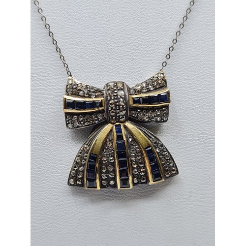 393 - A silver and gold diamond encrusted Sapphire bow, weight 6.5g 7 & length 40cms