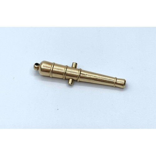 418 - Yellow metal match striker pendant in the shape of a canon, weight 7.1g and 5cm long