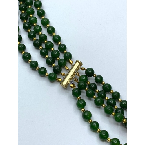 103 - A four row dark green jade necklace with gold filled ornamental beads. Length: 56-70 cm. Weight: 198... 