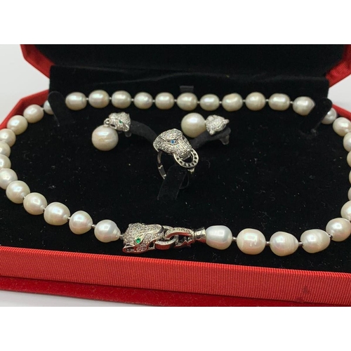 24 - A white pearl necklace, earrings and ring  set  in the Cartier Style. In original presentation box. ... 