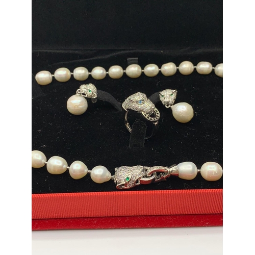 24 - A white pearl necklace, earrings and ring  set  in the Cartier Style. In original presentation box. ... 