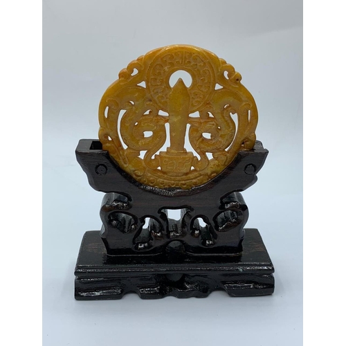 28 - A Chinese carved yellow-orange jade disc (amulet?) with a sword and two griffins among stylised clou... 