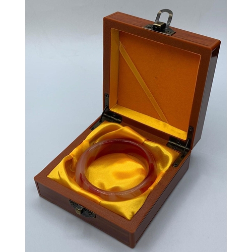 52 - A variegated carnelian bangle in a wooden presentation box. Weight: 72g, internal diameter: 6cm.