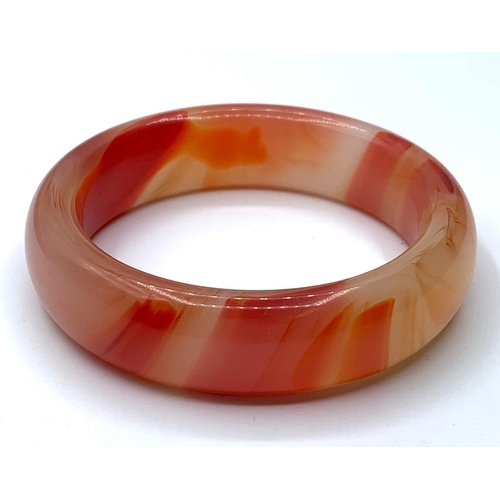 52 - A variegated carnelian bangle in a wooden presentation box. Weight: 72g, internal diameter: 6cm.