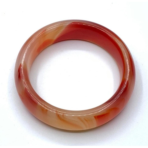 52 - A variegated carnelian bangle in a wooden presentation box. Weight: 72g, internal diameter: 6cm.