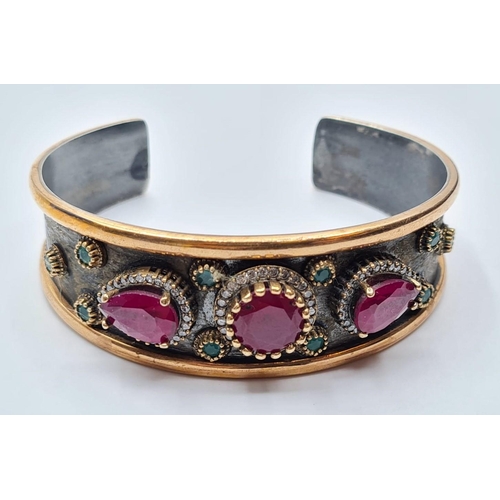 541 - Antique gilded silver bangle with inset ruby's and other stones, weight 34g