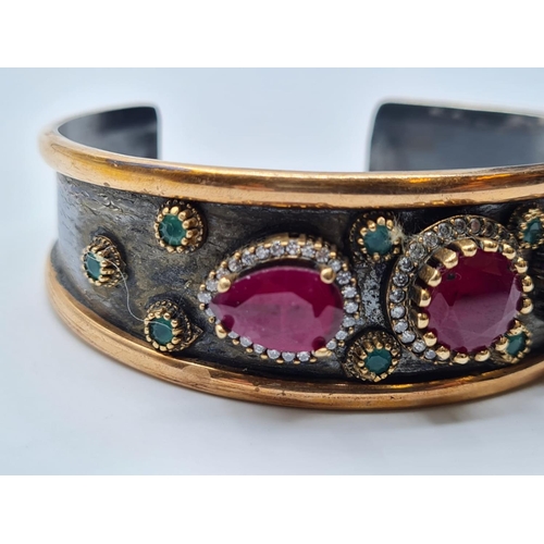 541 - Antique gilded silver bangle with inset ruby's and other stones, weight 34g