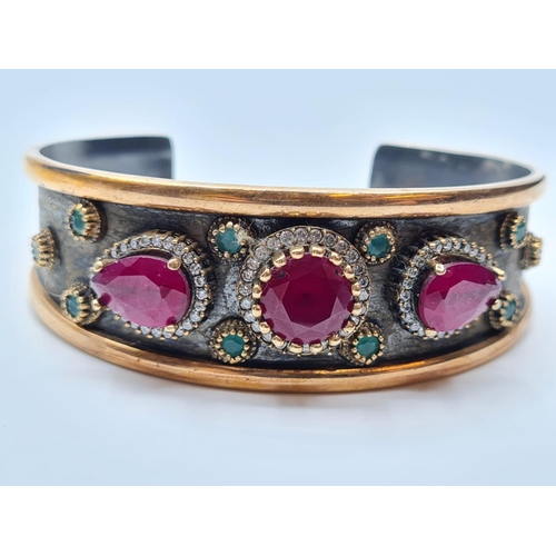 541 - Antique gilded silver bangle with inset ruby's and other stones, weight 34g