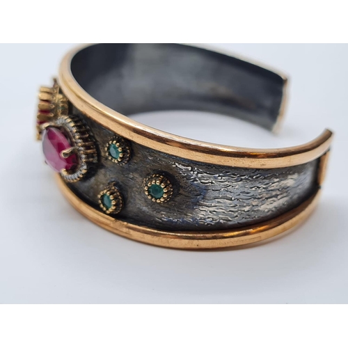 541 - Antique gilded silver bangle with inset ruby's and other stones, weight 34g