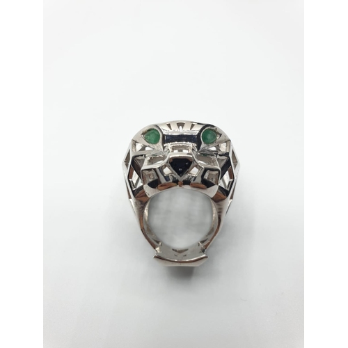 562 - An Art Deco, white metal (untested) Panther lattice ring with green emerald eyes, in the Cartier sty... 