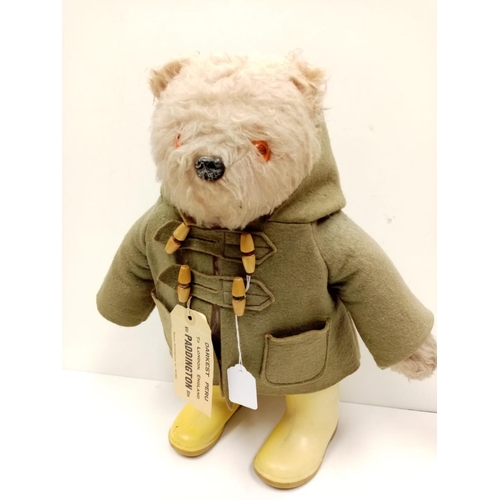 571 - An original 1970s Paddington bear in green felt coat, label and yellow Dunlop wellington boots. Stit... 