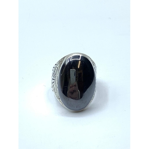 654 - Large silver ring with glossy dark grey stone to top. Engraved pattern to shoulders. Size T currentl... 