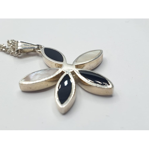 549 - Silver pendant having mother of pearl and black onyx set in flower form and presented on a silver ch... 