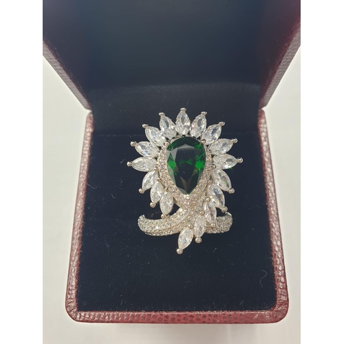 96 - An impressive silver (stamped S925) with green and clear gems. Ring size: N. In a presentation box.