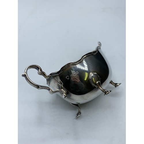 265 - Vintage silver sauce boat standing on three cabriole legs with serpentine edge and a scroll handle, ... 