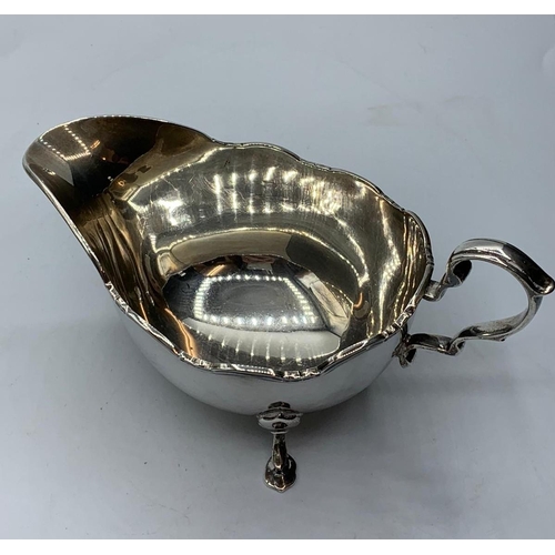 265 - Vintage silver sauce boat standing on three cabriole legs with serpentine edge and a scroll handle, ... 