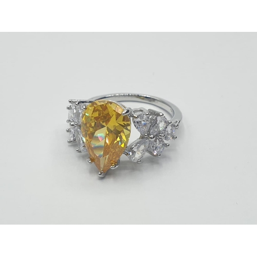 70 - A white metal (untested) ring with a pear shaped yellow topaz and white sapphires in an unusual pres... 