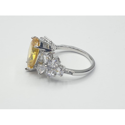 70 - A white metal (untested) ring with a pear shaped yellow topaz and white sapphires in an unusual pres... 