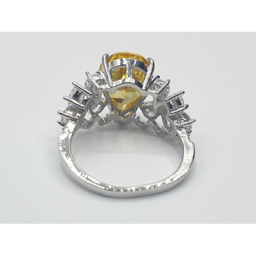 70 - A white metal (untested) ring with a pear shaped yellow topaz and white sapphires in an unusual pres... 