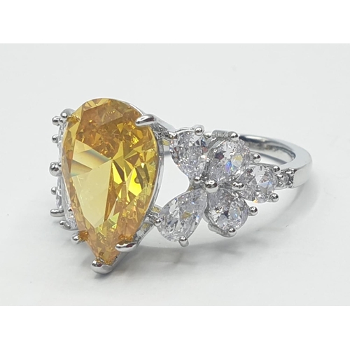 70 - A white metal (untested) ring with a pear shaped yellow topaz and white sapphires in an unusual pres... 