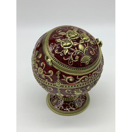 119 - A very ornamental,  global, bronze and dark red enamel, ashtray on a
circular base. Height: 12cm, wi... 