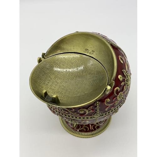 119 - A very ornamental,  global, bronze and dark red enamel, ashtray on a
circular base. Height: 12cm, wi... 