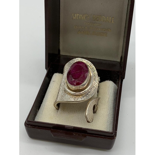 126 - An unusual artisan’s silver (stamped 925) ring with a big faceted oval ruby      
central stone in i... 