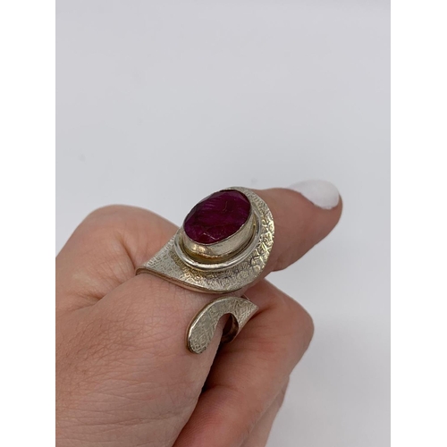 126 - An unusual artisan’s silver (stamped 925) ring with a big faceted oval ruby      
central stone in i... 