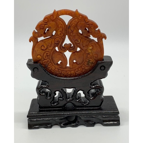 49 - A Chinese, hand carved on both sides and pierced, orange hard stone amulet
representing two symmetri... 