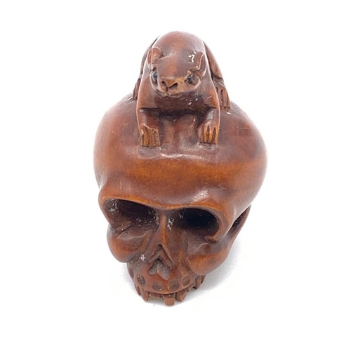 84 - A finely carved boxwood netsuke representing a human skull with a rat
Although the skull represents ... 