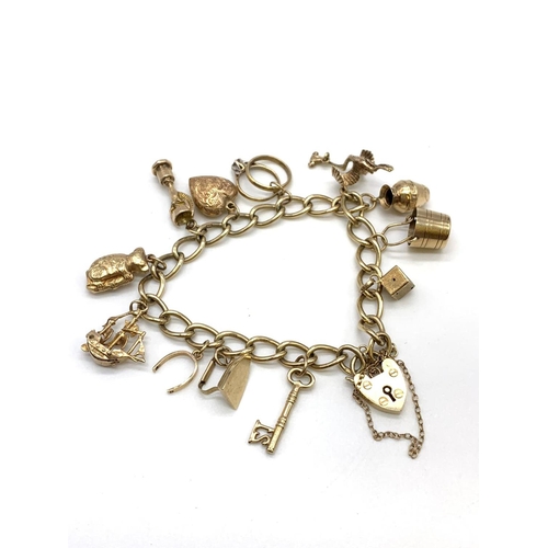 90 - 9ct Gold Charm Bracelet with 12 charms and Heart padlock 28.4g and 16cm length