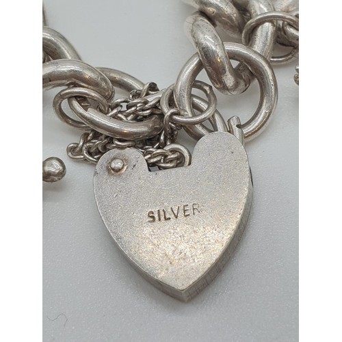 302 - Vintage silver charm bracelet with 12 charms and heart padlock, weight 63.65g and 18cm long approx